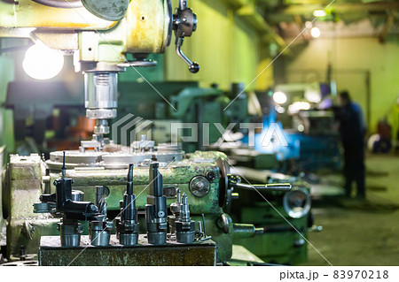 A set of metalworking tools in front of manual vertical milling and boring oldschool machine indoors 83970218