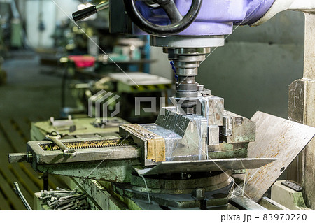 A process of old-style manual milling in weathered vise with liquid coolant., Close-up with selective focus and background bliur, A process of old-style manual milling in weathered vise with liquid coolant., Close-up with selective focus and background bliur, 83970220