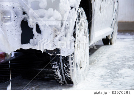 a car covered by soap foam while washing indoors - close-up low position view from back with selective focus 83970292