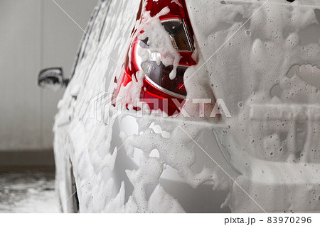 a car covered by soap foam while washing indoors - close-up wiew from back with selective focus a car covered by soap foam while washing indoors - close-up wiew from back with selective focus 83970296