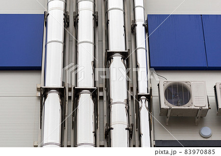 Chrome ventilation pipes on the outside wall of the white and blue Industrial building 83970885