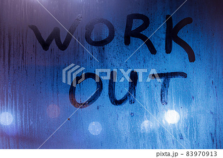 The words work out written on night sweaty window glass with blurred blue light in the background 83970913
