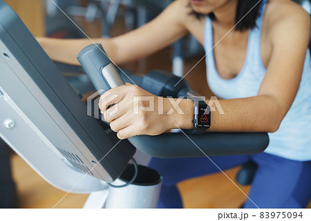 Pulse app display on smartwatch in the hands of a woman exercising in sports club 83975094