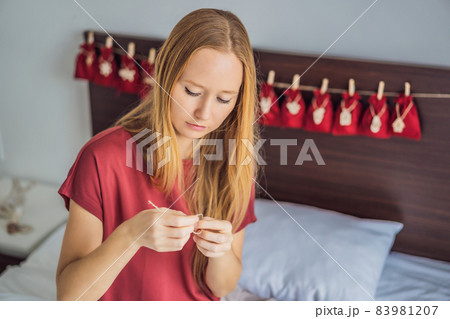 Woman making Christmas advent calendar. Pouches on a rope 83981207