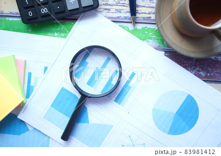 financial data and magnifying glass on blue . financial data and magnifying glass on blue . 83981412
