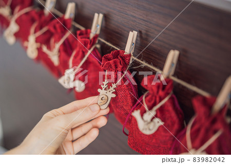 Woman making Christmas advent calendar. Pouches on a rope Woman making Christmas advent calendar. Pouches on a rope 83982042