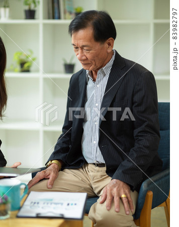 A middle-aged executive businessman in a formal suit sits in an office A middle-aged executive businessman in a formal suit sits in an office 83982797