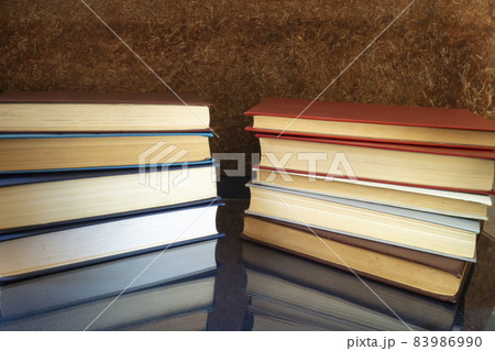 The Stack of the books rests upon turn blue the table with reflection. The Stack of the books rests upon turn blue the table with reflection. 83986990