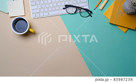 Top view wireless keyboard, coffee cup and notebook on colorful background. 83987239
