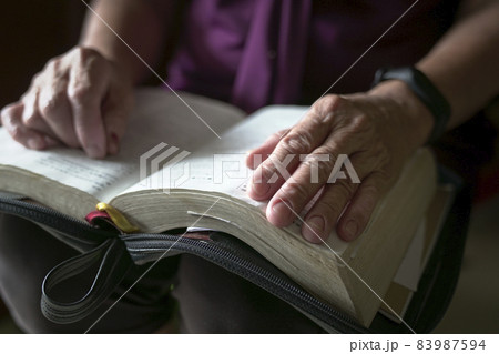 Elderly woman hand on an open book Elderly woman hand on an open book 83987594