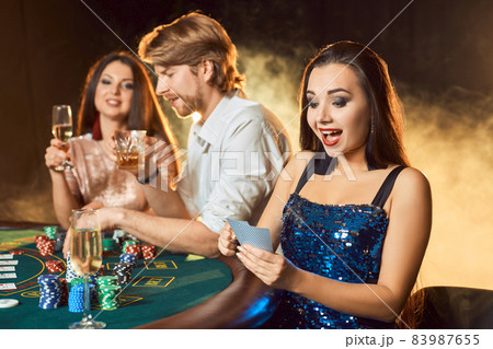 Group of an elegant people playing poker at the gambling house. Focus on a emotional brunette in a blue shiny dress Group of an elegant people playing poker at the gambling house. Focus on a emotional brunette in a blue shiny dress 83987655