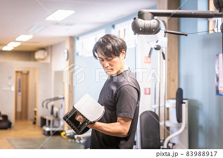 スポーツジムでブロックダンベルを使う男性 83988917