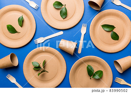 set of empty reusable disposable eco-friendly plates, cups, utensils on light white colored table background. top view. Biodegradable craft dishes. Recycling concept. Close-up 83990502