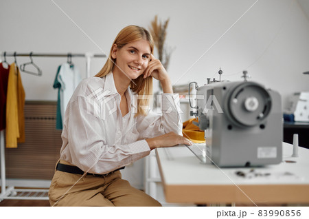 Seamstress works on sewing machine at workplace 83990856