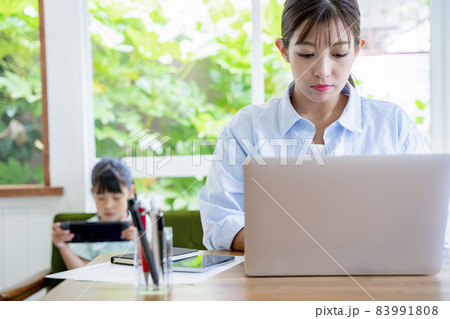 自宅で仕事をする母親とゲームをする子供 自宅で仕事をする母親とゲームをする子供 83991808