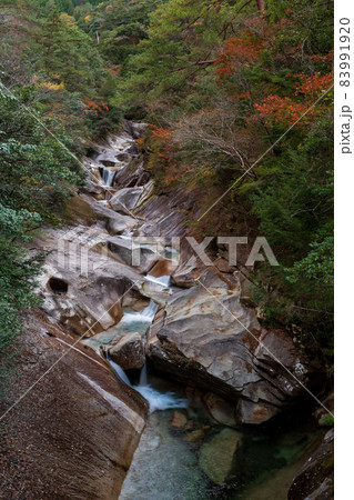 紅葉の色着く藤河内渓谷にエメラルドグリーンの川が流れる風景 83991920