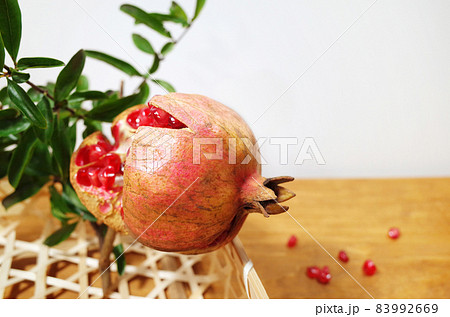 木の板に籠に入った割れた石榴の実 83992669