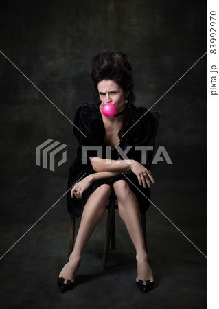 Classic retro portrait of young beautiful woman in image of medieval royal person in black dress isolated on dark vintage background. Classic retro portrait of young beautiful woman in image of medieval royal person in black dress isolated on dark vintage background. 83992970