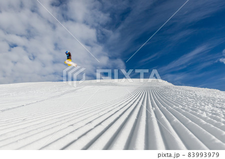 Close-up straight line rows of freshly prepared groomed ski slope piste with bright shining sun and clear blue sky background. Snowcapped mountain downhill landscape at europe winter skiing resort Close-up straight line rows of freshly prepared groomed ski slope piste with bright shining sun and clear blue sky background. Snowcapped mountain downhill landscape at europe winter skiing resort 83993979