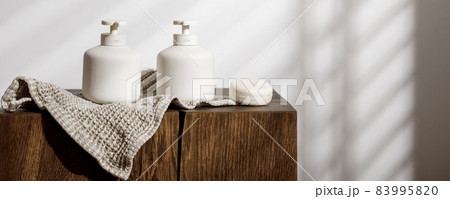 Soap and lotion white ceramic dispensers, organic linen towel and dry shampoo on solid oak stump. Daily body care, spa and wellness zero waste bathroom concept 83995820