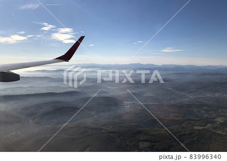 landscape view out of an airplane with mountains and clouds landscape view out of an airplane with mountains and clouds 83996340