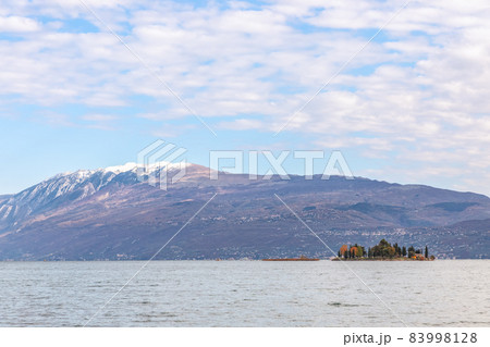 Small Rabbit island in Lake Garda against the background of the Alps (Autumn period) 83998128