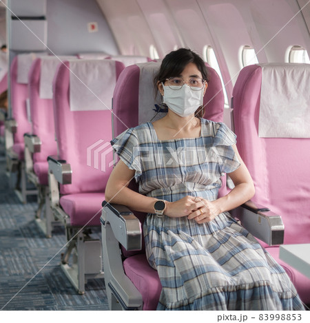 Young woman wearing protective face mask in airplane or public transportation, protection Coronavirus disease infection, Asian tourist ready to travel. Next Normal and reopening concept 83998853