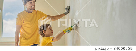 Man with his son makes repairs at home, he teaches children to plaster the walls with a spatula in his hands BANNER, LONG FORMAT Man with his son makes repairs at home, he teaches children to plaster the walls with a spatula in his hands BANNER, LONG FORMAT 84000559