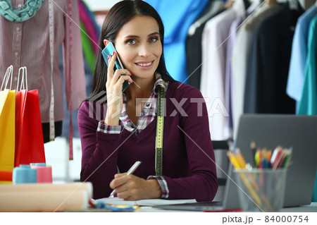 Young woman fashion designer talking on the phone at workplace in atelier 84000754