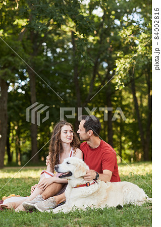 Couple Sitting on Grass with Dog 84002816