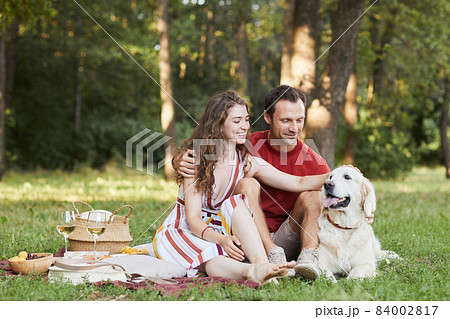 Couple Enjoying Picnic Outdoors with Dog 84002817