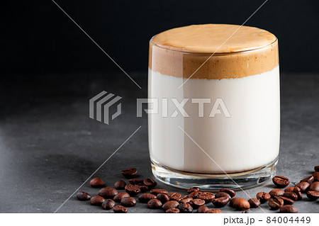 Dalgona coffee on a dark background. A glass of trendy Korean ice drink made from milk and fluffy foam. Place for text 84004449