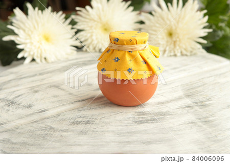 Pot of honey and wooden honey stick are on a table. Pot of honey and wooden honey stick are on a table. 84006096