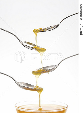 Fresh flower honey drips from a spoon into a spoon on a white background. Organic vitamin food. Fresh flower honey drips from a spoon into a spoon on a white background. Organic vitamin food. 84006809