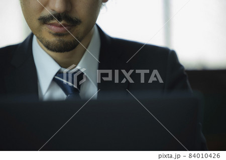 パソコンを見る髭の男性 84010426