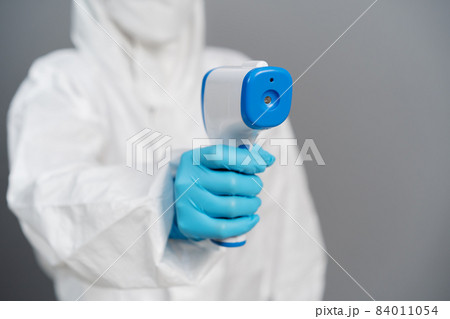 doctor in protective PPE suit scanning with infrared thermometer doctor in protective PPE suit scanning with infrared thermometer 84011054