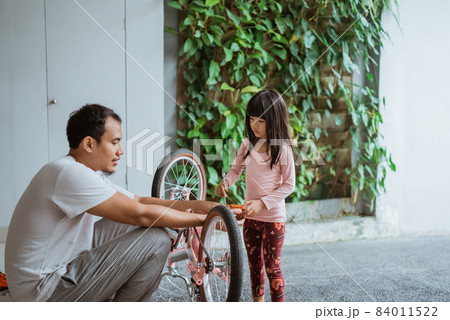 little girl holding a wrench while pedaling with her father little girl holding a wrench while pedaling with her father 84011522