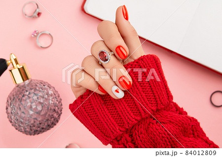 Manicured womans hand in warm wool red sweater. Fashionable valentines day nail design 84012809