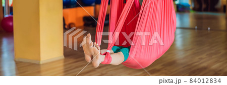 Senior mature woman practices anti-gravity yoga with a hammock in a studio. Lifestyle BANNER, LONG FORMAT 84012834
