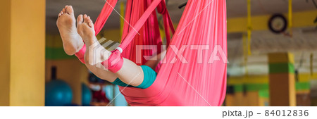 Senior mature woman practices anti-gravity yoga with a hammock in a studio. Lifestyle BANNER, LONG FORMAT Senior mature woman practices anti-gravity yoga with a hammock in a studio. Lifestyle BANNER, LONG FORMAT 84012836