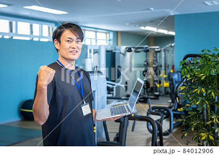 スポーツジムで働くスポーツトレーナー（パソコン・ガッツポーズ） 84012906