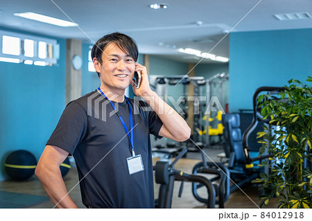 スポーツジムで働くスポーツトレーナー（スマホ・話す） 84012918