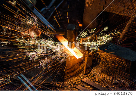 Blacksmith forging the molten metal on the anvil with spark fireworks Blacksmith forging the molten metal on the anvil with spark fireworks 84013370