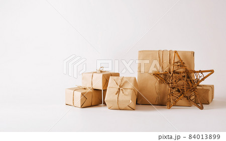 Handmade star, gifts in simple paper packaging light background. Festive composition for Christmas or New Year Handmade star, gifts in simple paper packaging light background. Festive composition for Christmas or New Year 84013899