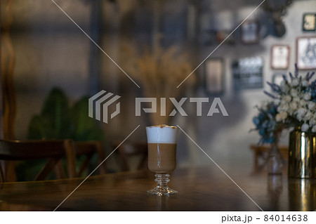 Glass cup with latte is on the table in coffee shop. Glass with caramel cappuccino on the table in the restaurant. Photo for the menu, advertising 84014638