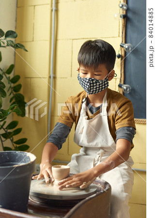 Asian schoolboy in protective mask sculpting clay pot Asian schoolboy in protective mask sculpting clay pot 84014885
