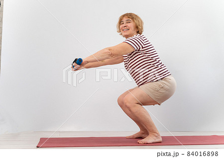 Elderly woman doing squats on a white - Stock Photo [84016898