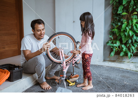 Asian father and daughter repairing bicycle together Asian father and daughter repairing bicycle together 84018263