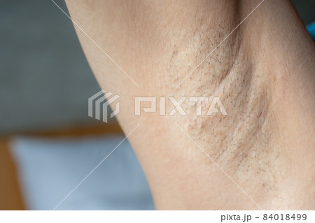 Close up of woman showing her unshaved armpit. Unshaven women often meet other criteria for traditional feminine beauty. 84018499
