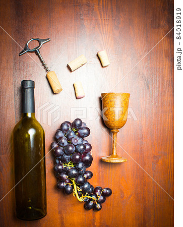 Bottle of wine with corkscrew on wooden background Bottle of wine with corkscrew on wooden background 84018919